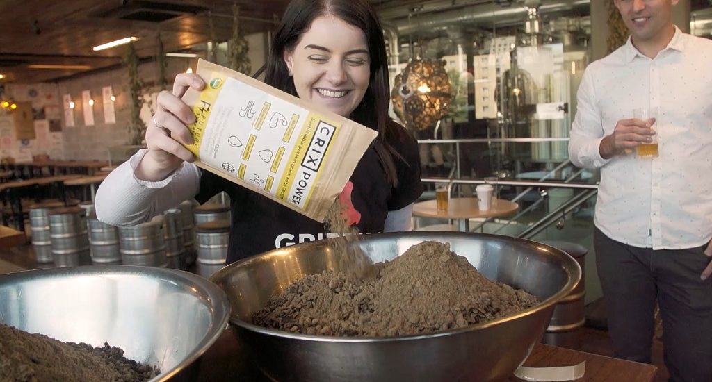 Canberra Innovation Network team member pouring Cricket Powder into the mixture for the collaborative beer with BentSpoke Brewing