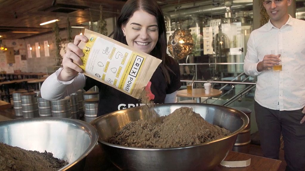 Canberra Innovation Network team member pouring Cricket Powder into the mixture for the collaborative beer with BentSpoke Brewing