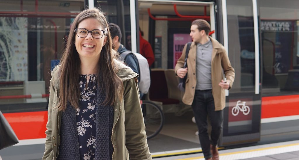 Woman smiles walking off tram