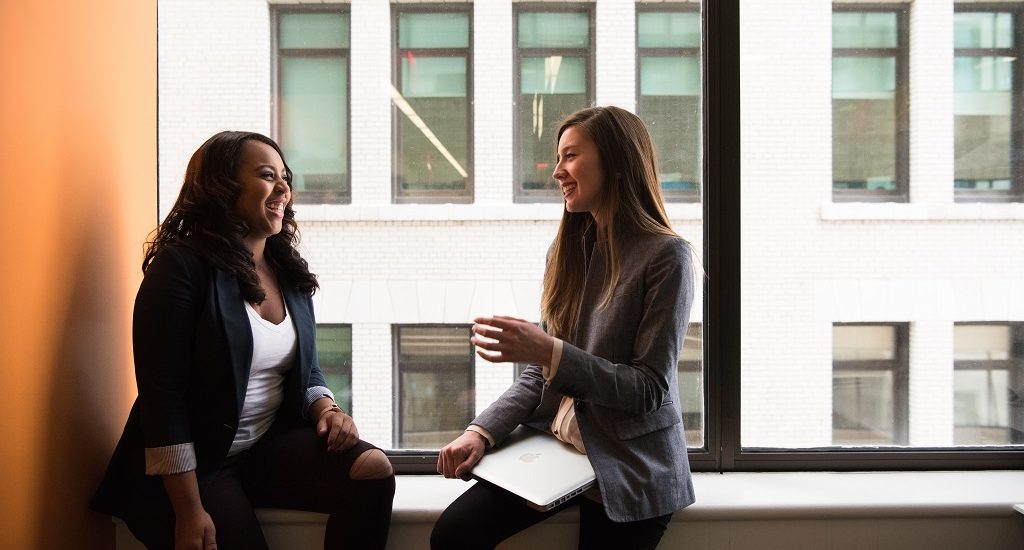 Two women chatting by a window