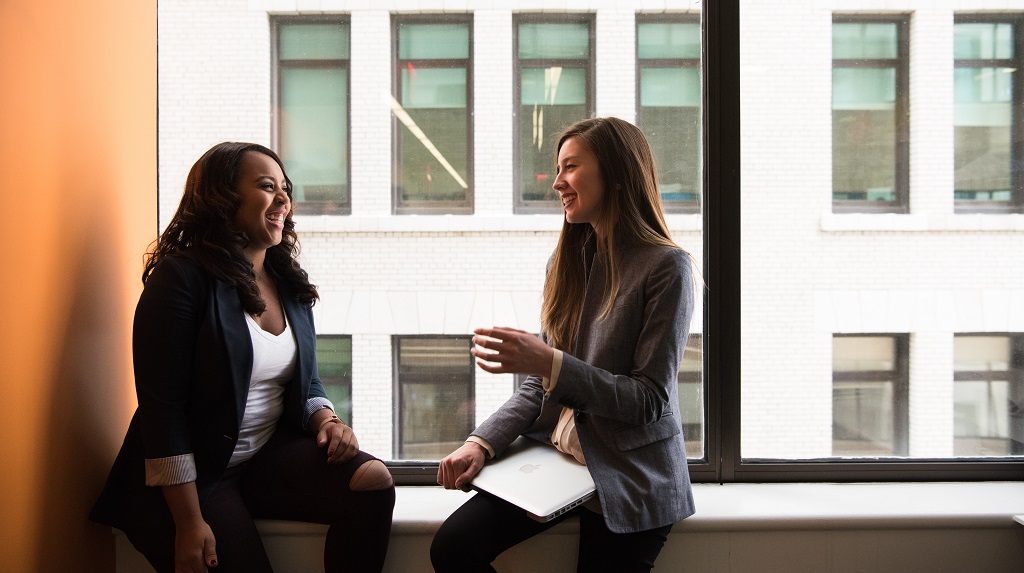Two women chatting by a window